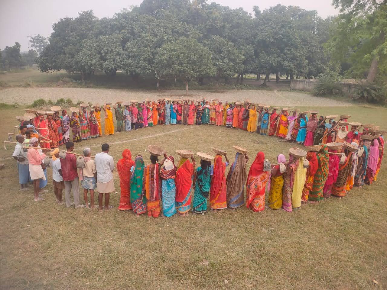 NREGA workers standing in a large circle on an open field
