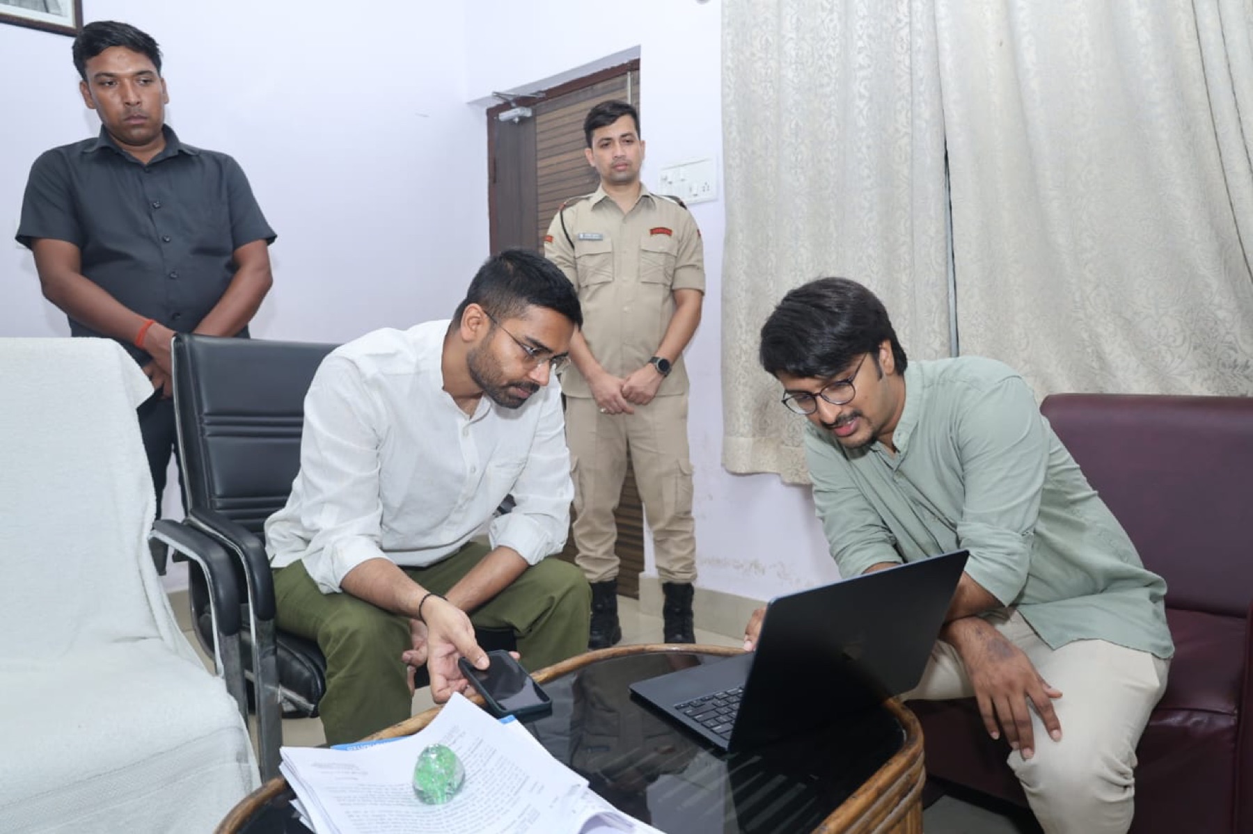 Team members reviewing data on a phone and laptop with officials present