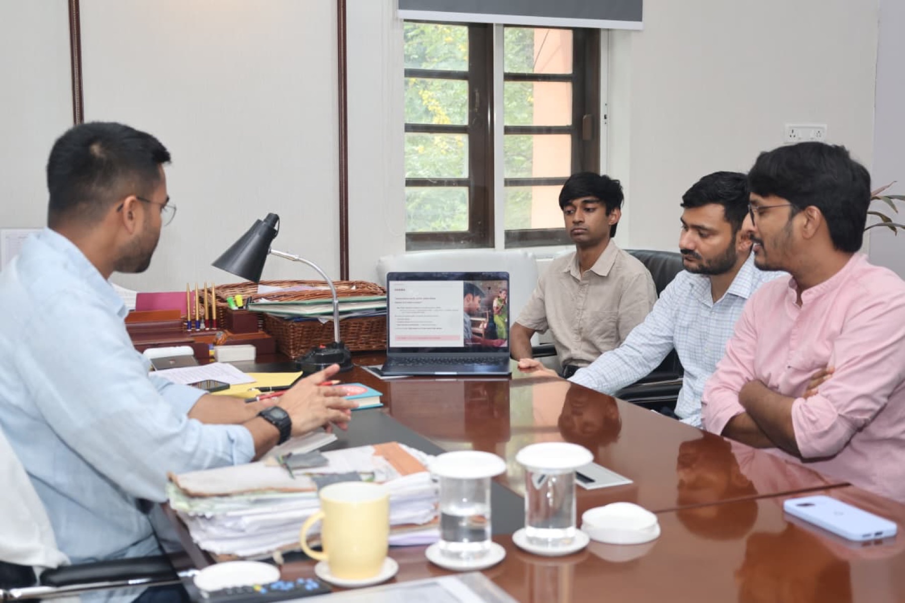 GRAMA team presenting research findings on a laptop to an official in a government office